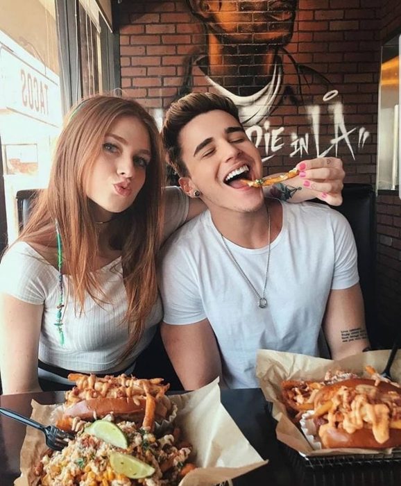 Pareja feliz comiendo papas en un restaurante