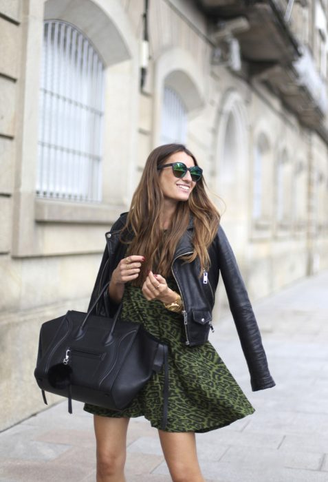 Chica joven usando un vestido verde de animal print, lentes oscuros y bolsa negra de mano