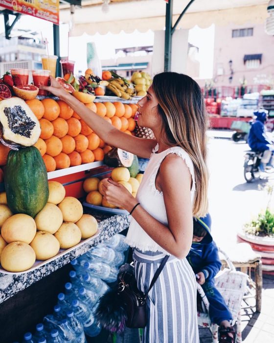 Chica joven en el mercado comprando jugos naturales y frutas