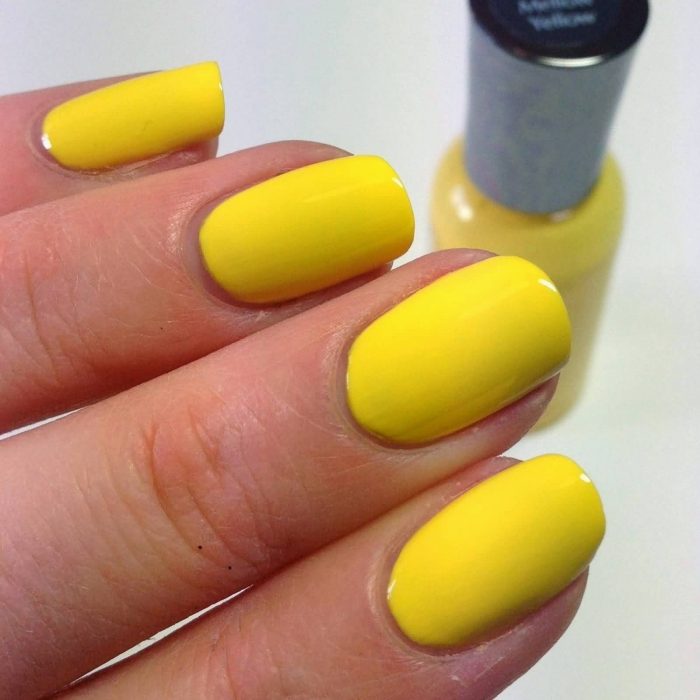 manos de mujer con uñas color amarillo