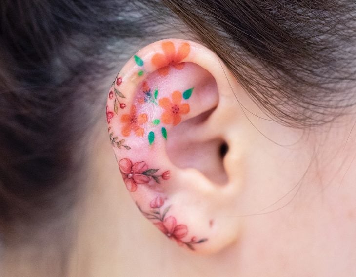Chica con las orejas tatuadas con flores 