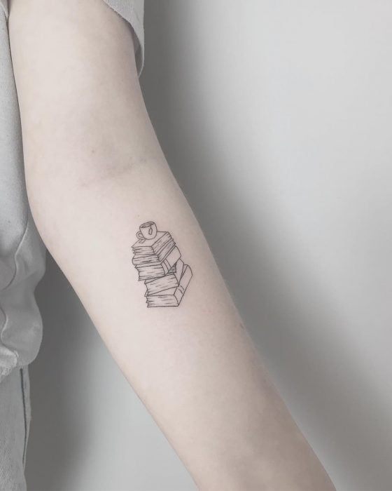 Chica con un pequeño tatuaje de libros en su brazo