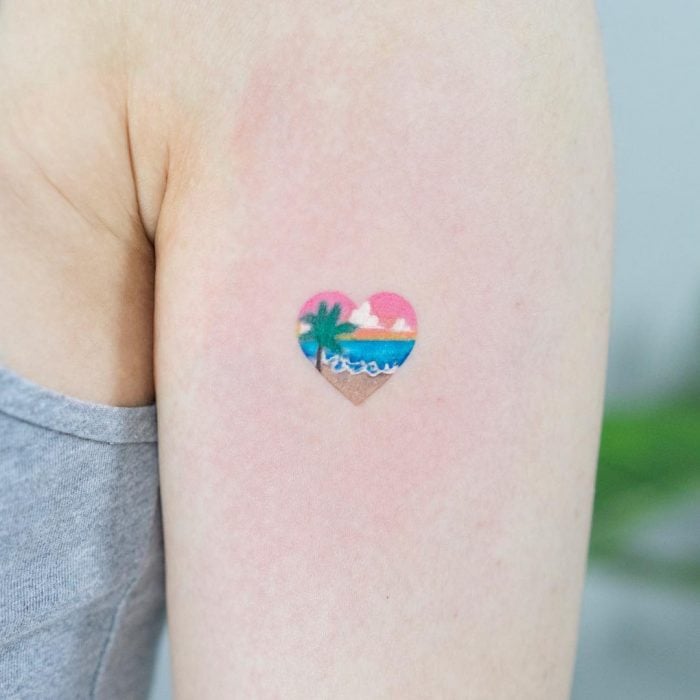 Chica con un tatuaje de un corazón que tiene una playa dentro 