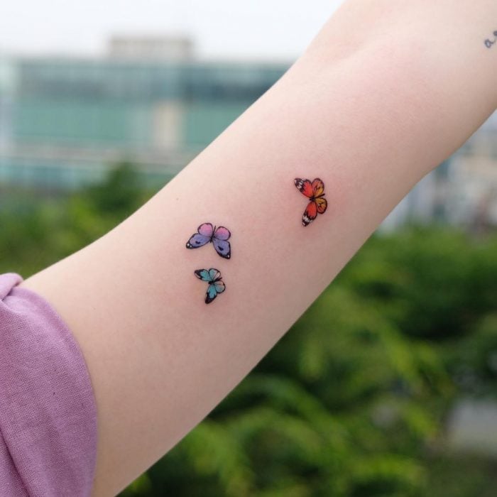 Chica con un tatuaje de tres mariposas de diferentes colores