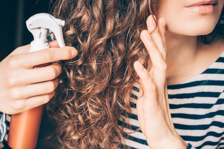 Chica aplicando tratamiento en su cabello chino