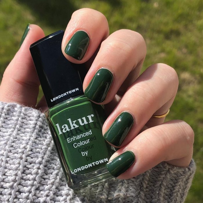 manos de mujer con uñas color verde 