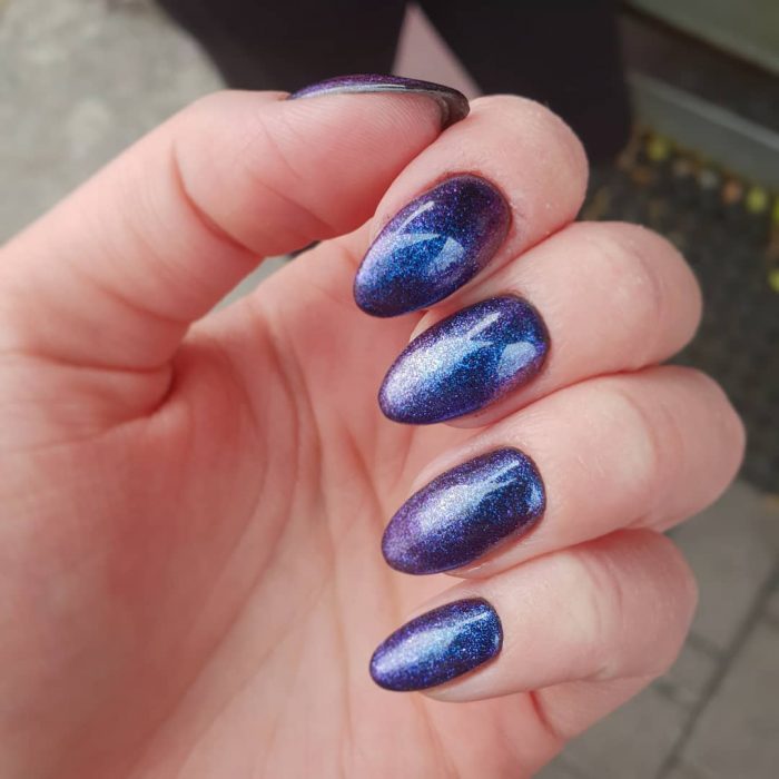 manos de mujer con uñas color azul metálico 