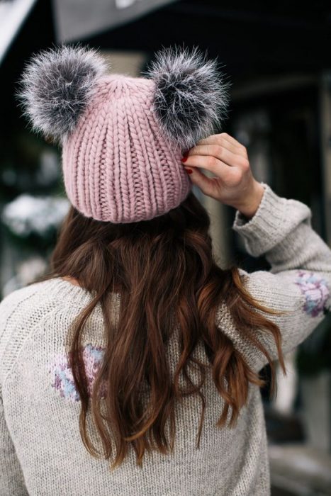 mujer con gorro rosa y pompones grises 