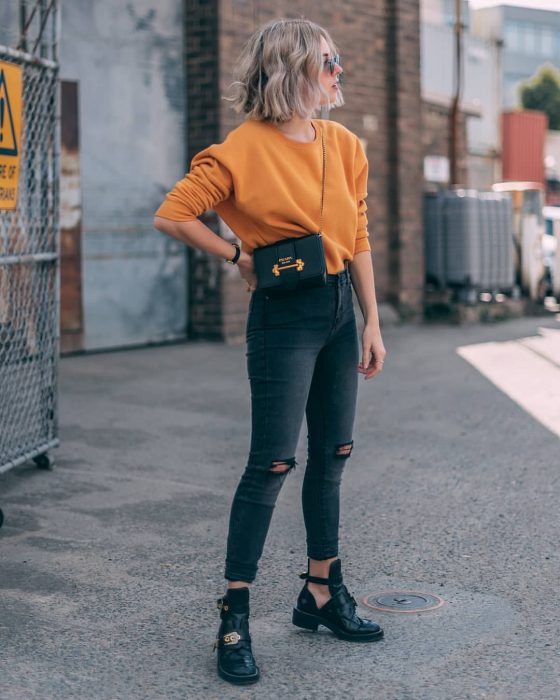 mujer rubia con suéter naranja 