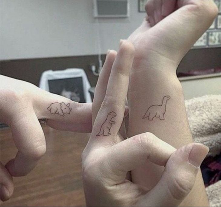 tatuaje de dinosaurios en manos y brazos 