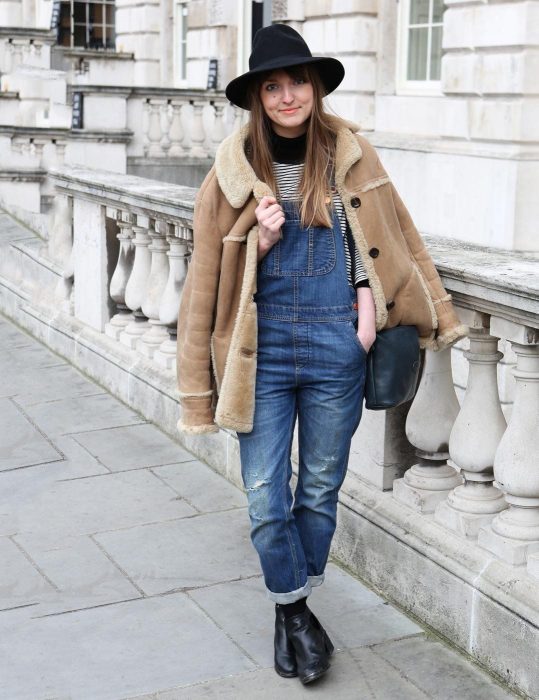 Chica usando un overol con botines y sombrero 