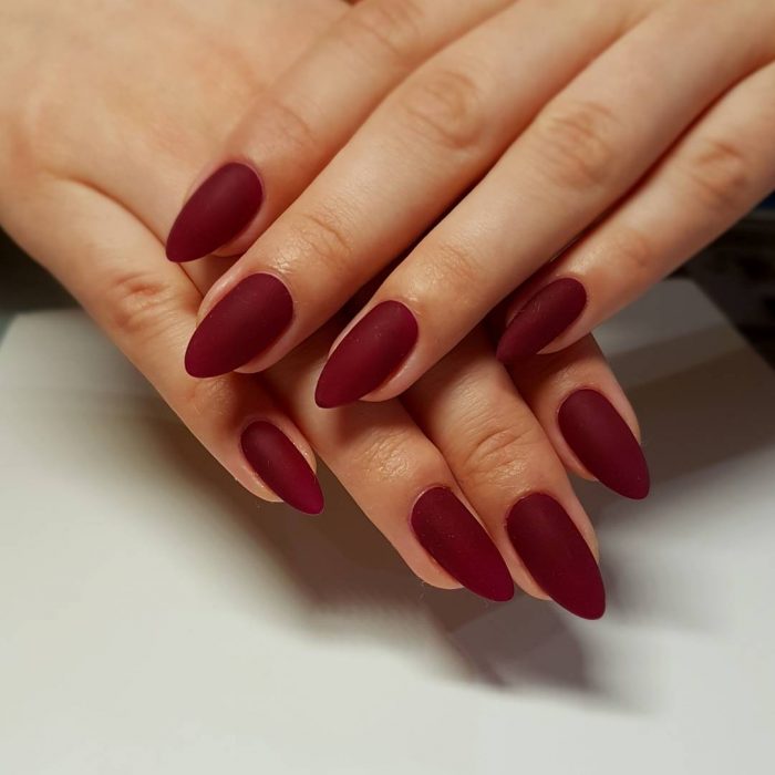 manos de mujer con uñas color vino 