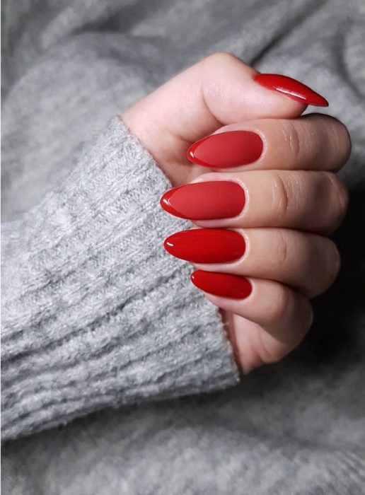 manos de mujer con uñas color rojo 