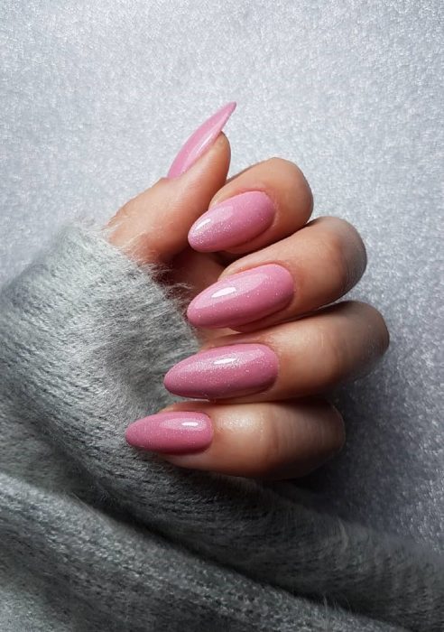 manos de mujer con uñas color rosa 