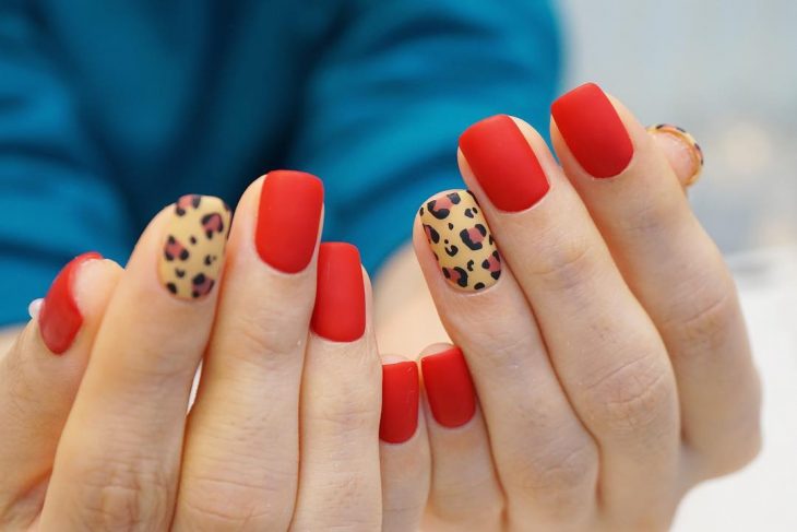 manos de mujer con uñas rojas y leopardo 