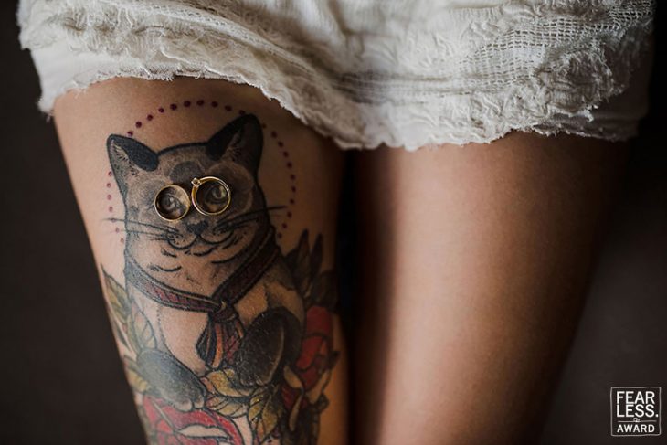 tatuaje de gato en pierna de mujer con vestido blanco y anillos 