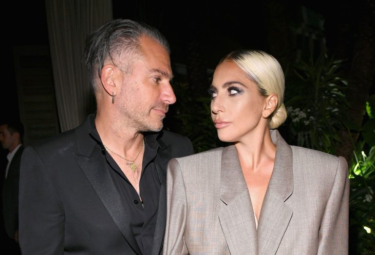 Lady Gaga y Christian Carino, mujer rubia con traje beige y hombre con traje negro