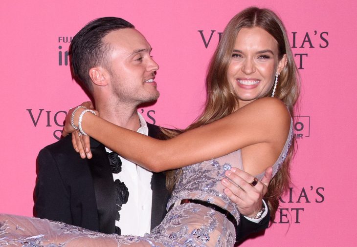 Josephine Skriver y Alezander DeLeon, hombre de traje cargando a mujer de vestido de encaje