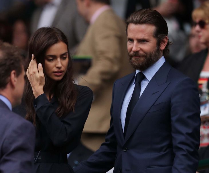 Bradley Cooper e Irina Shyk, mujer de cabello largo con traje y hombre con barba y traje