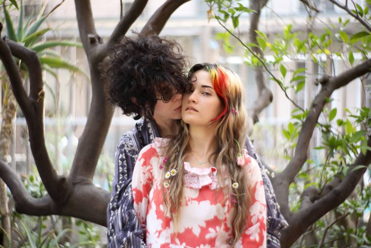 LP y Lauren Ruth Ward, pareja abrazada, mujer de cabello chino y lentes oscuros y mujer de cabello largo con cabello teñido de arcoiris