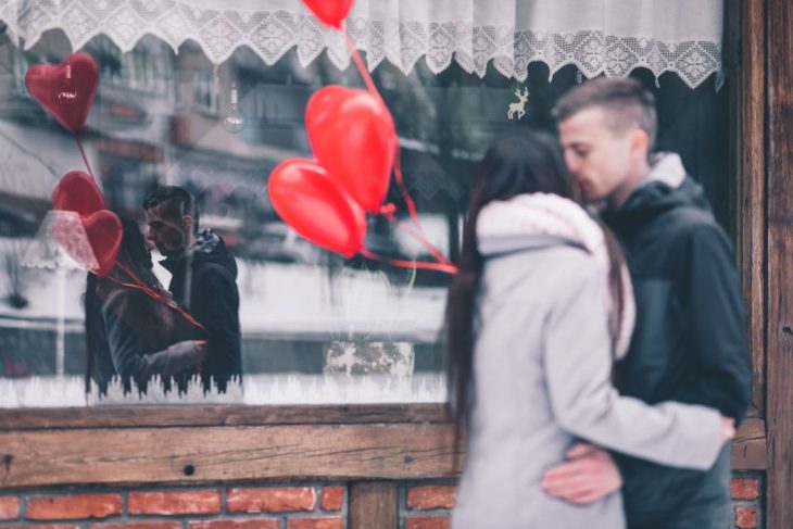 pareja d enovios besándose frente a un cristal