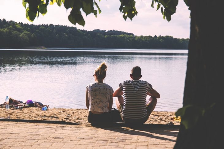 pareja de novios sentados frente a un lago 