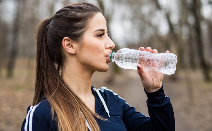 Chica de cabello largo y coleta tomando agua natural