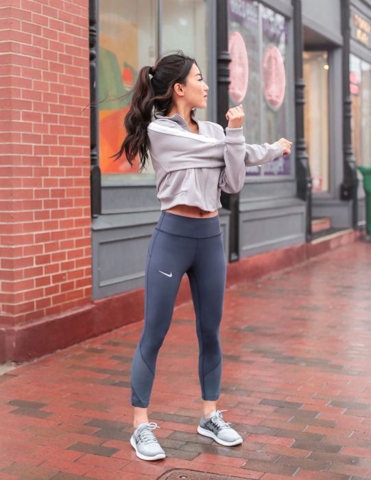 Chica con traje deportivo gris haciendo ejercicios de calentamiento