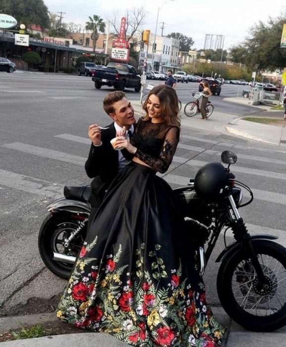 Pareja vistiendo ropa elegante sentados sobre una motocicleta en la calle