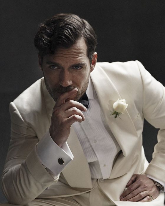 Henry Cavill, hombre de cabello corto con traje blanco y una mano en la boca