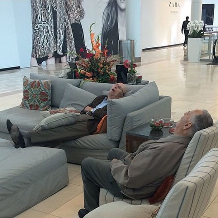 Hombres esperando que su mujer salda de las tiendas en el centro comercial 