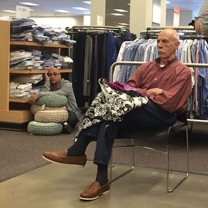 Hombres esperando que su mujer salda de las tiendas en el centro comercial 