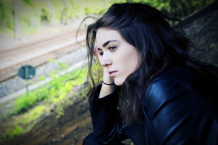 mujer morena con chamarra de piel mirando por ventana 