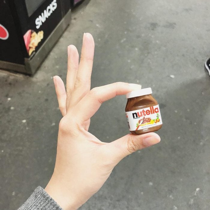 Chica sosteniendo con dos dedos un mini frasco de nutella