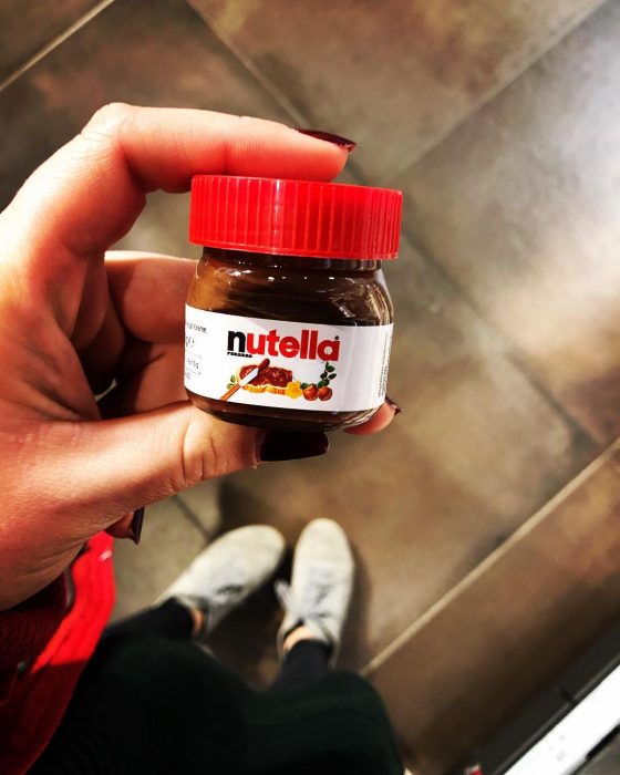 Chica sosteniendo con dos dedos un mini frasco de nutella