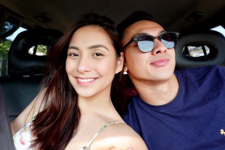 Pareja de novios en un carro, chica con vestido de tirantes y hombre con lentes y playera azul