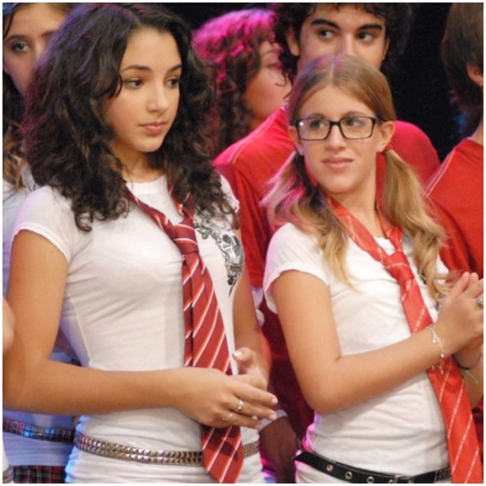 Thelma Fardín en la serie infantil Patito feo vestida con blusa blanca y corbata roja al lado de su amiga