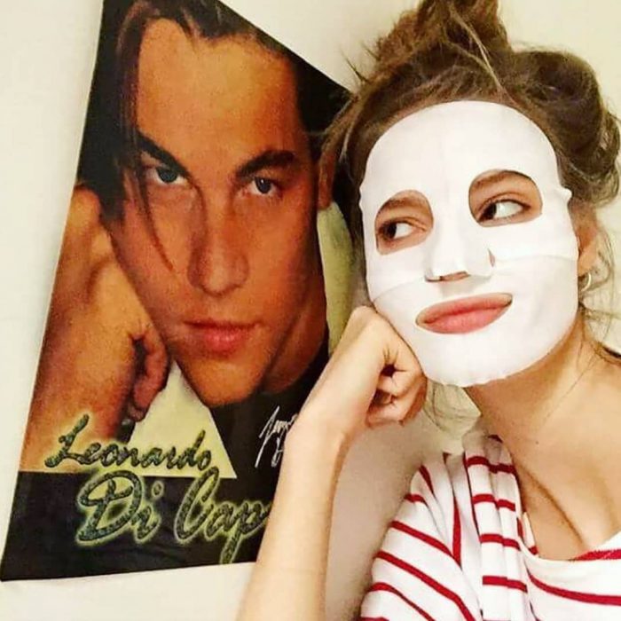 Chica utilizando una mascarilla al lado de un poster de Leonardo DiCaprio