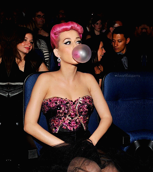Katy Perry con cabello rosa haciendo una bomba de chicle