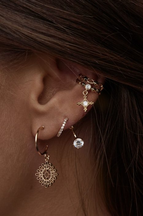 oreja de mujer con pearcings y aretes 