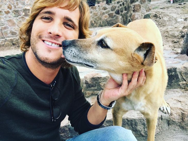 hombre rubio sonriendo junto a perro