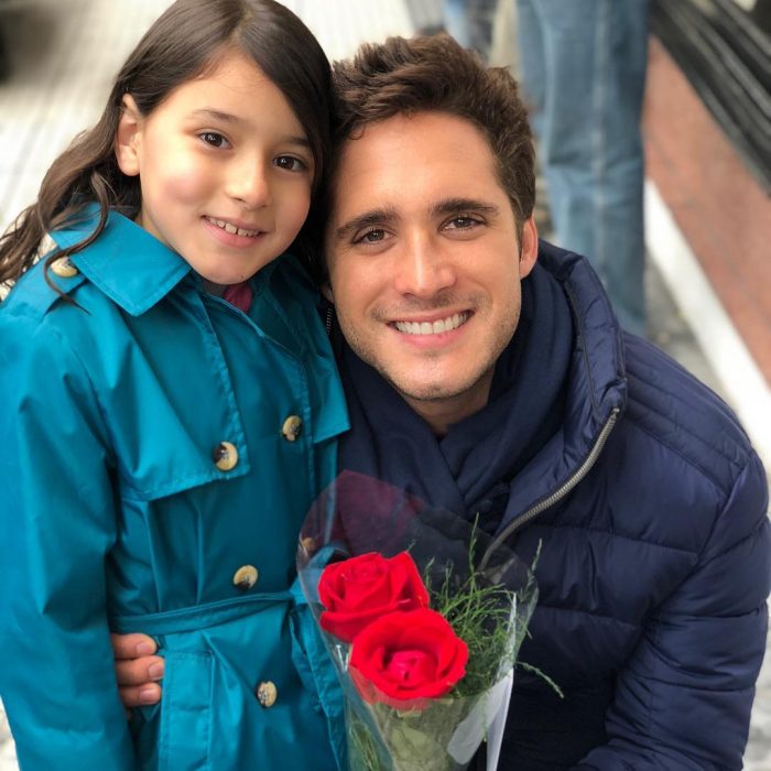 niña junto a hombre y flores rojas 