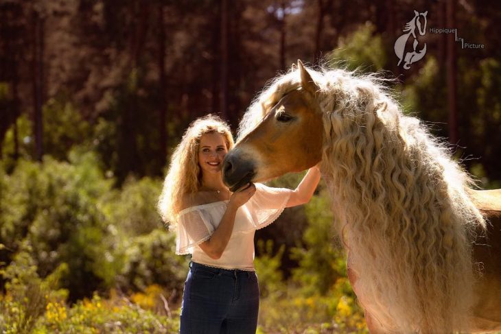 mujer rubia con cabello rizado arriba de un caballo 