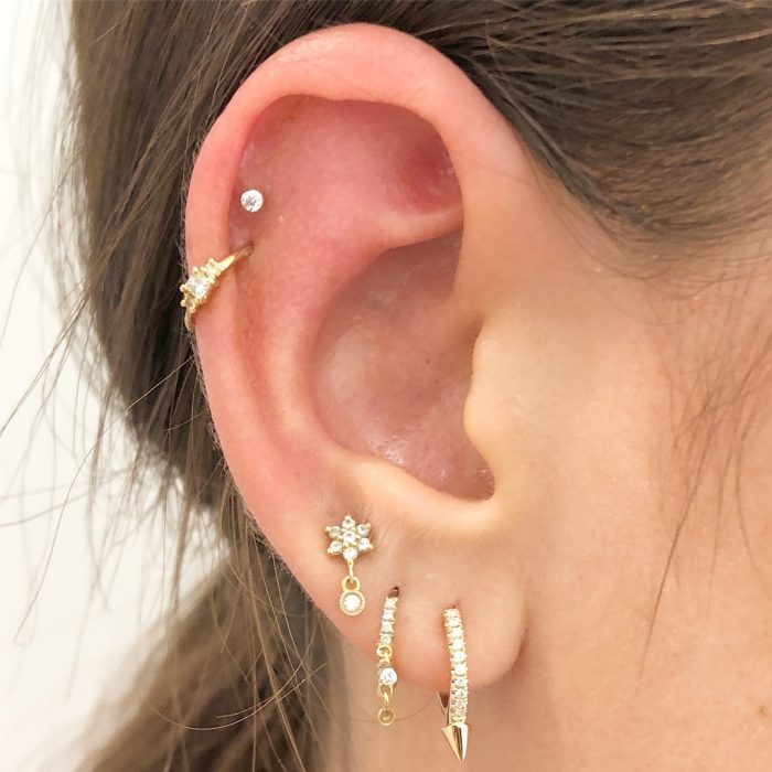 oreja de mujer con pearcings y aretes 