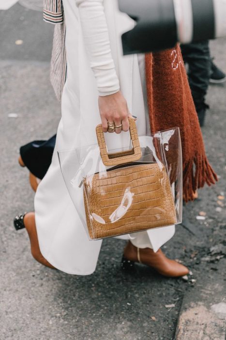 mujer con traje blanco y zapatos y bolsa de plástico y bufanda 