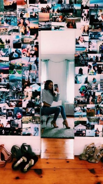 mujer con pared de fotos y espejo en su cuarto 