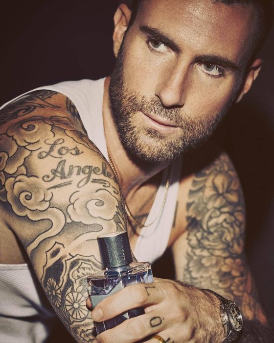 Adam Levine de Maroon 5, hombre con tatuajes, barba y playera blanca con perfume