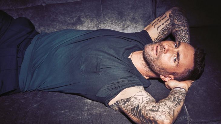 Adam Levine de Maroon 5, hombre con tatuajes, barba y playera gris