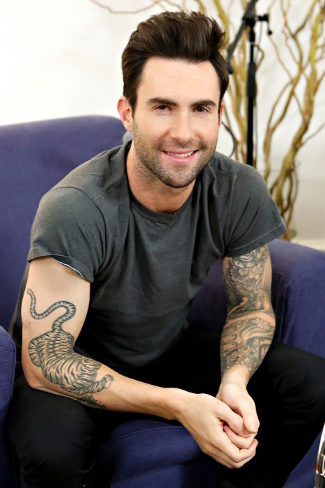 Adam Levine de Maroon 5, hombre con tatuajes, barba y playera gris