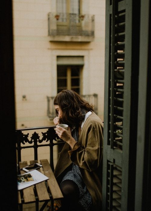 chica tomando café en un balcon 